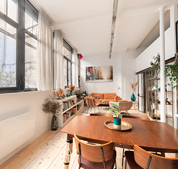 Séjour lumineux d'un appartement parisien, table dressée près de la fenêtre